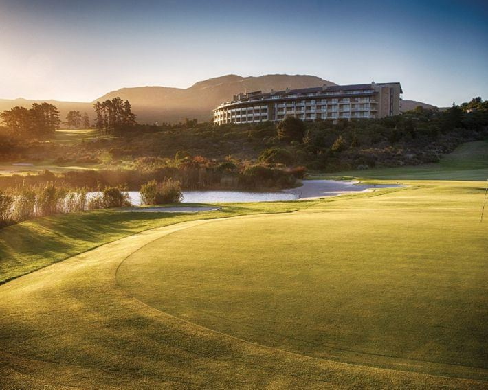The Arabella hotel on its rise above the golf course in early morning light, mountains behind