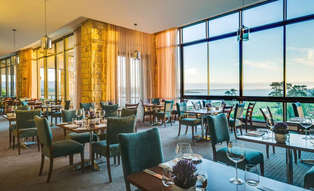 A restaurant with tables beside tall windows overlooking the lagoon