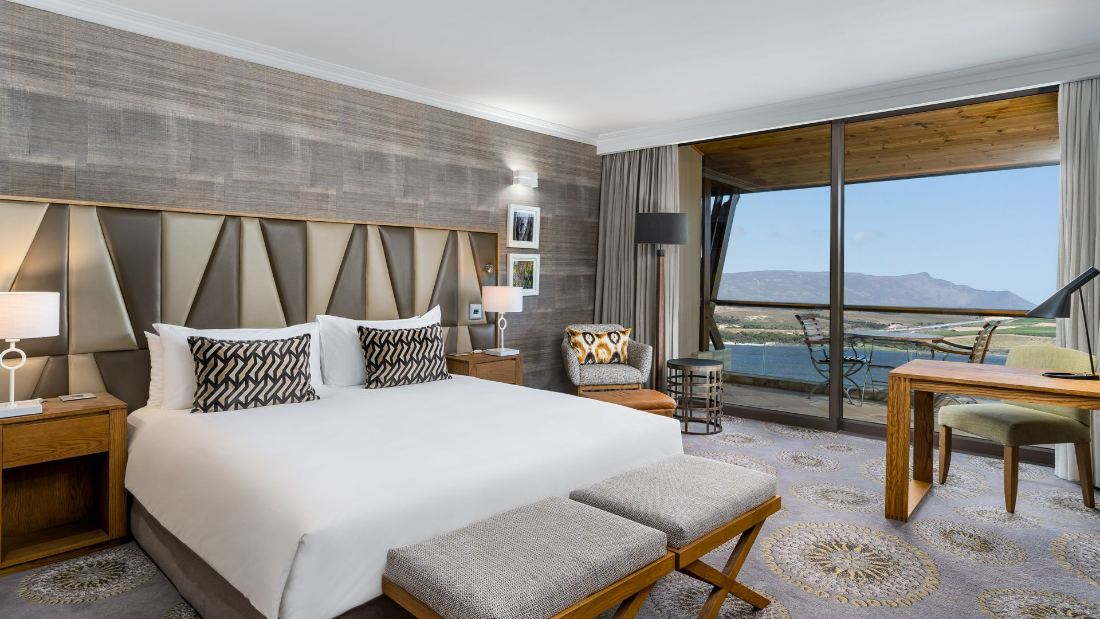 A hotel bedroom with a large window looking out over the lagoon and mountains