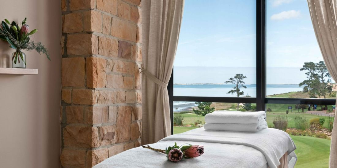 A massage bed beside a window looking out over the lagoon