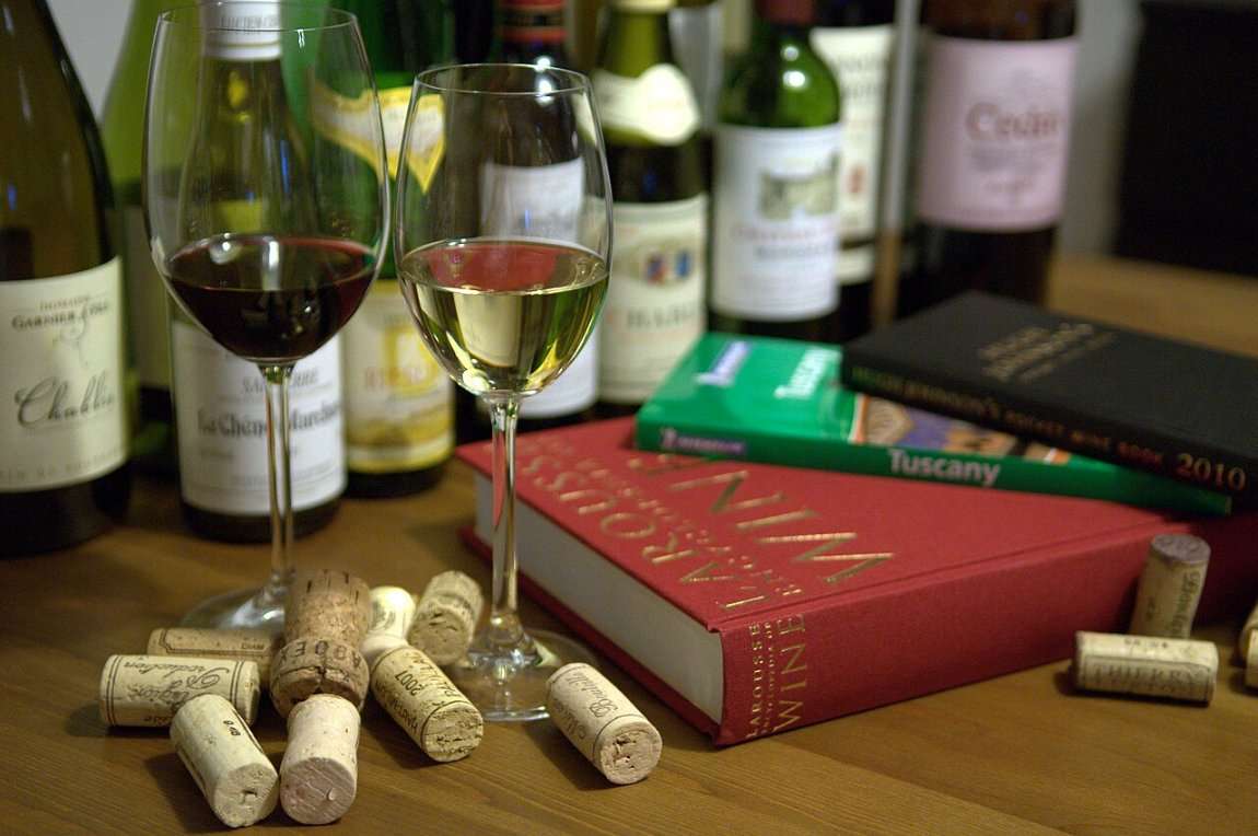 Wine bottles and glasses on a table among books and corks
