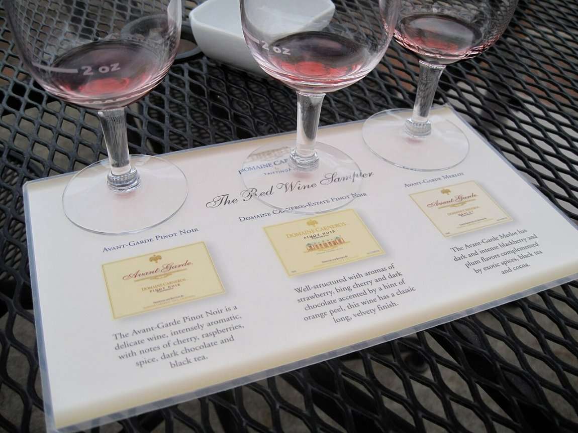 Three glasses of red wine on a tasting mat with notes