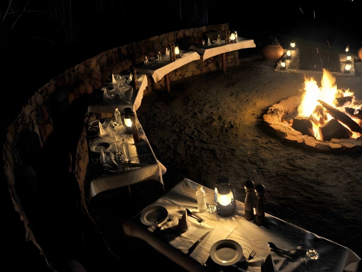 Dinner tables set around a fire in the boma at night