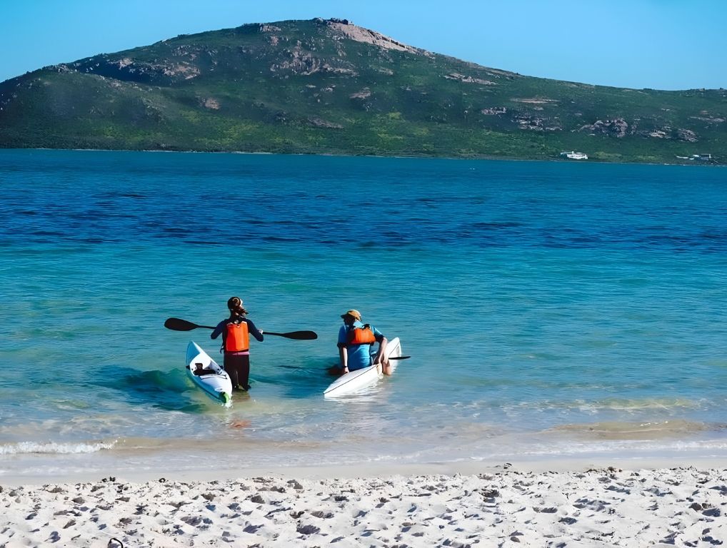 Two kayakers setting off from the white beach into the lagoon