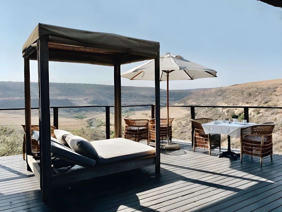 A shaded daybed and a table on the deck above the valley