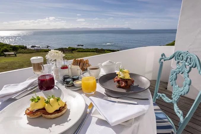Breakfast laid on a balcony table, with Walker Bay beyond