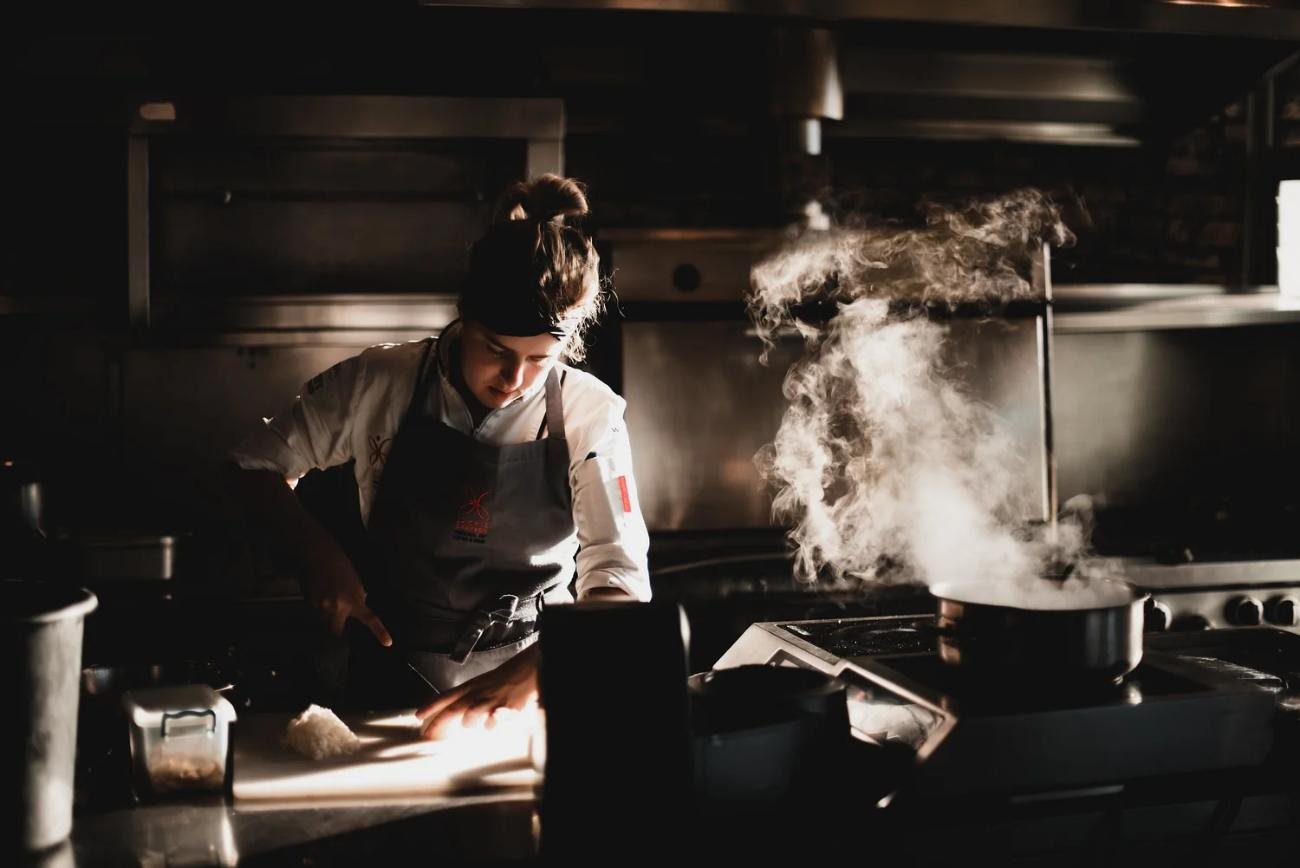 Chefs at work in the open kitchen, with flames rising