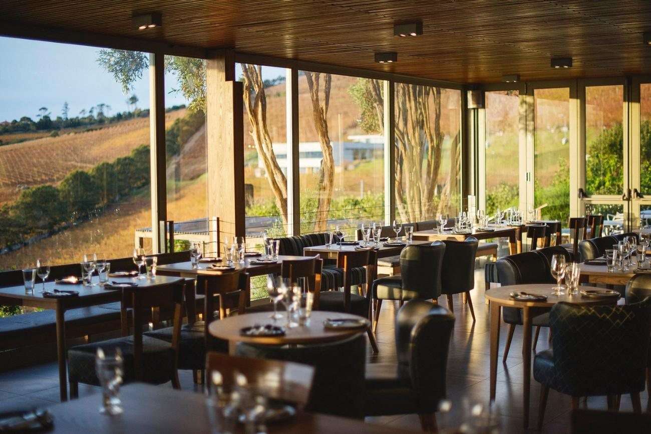 A dining room with glass walls and a view of the valley