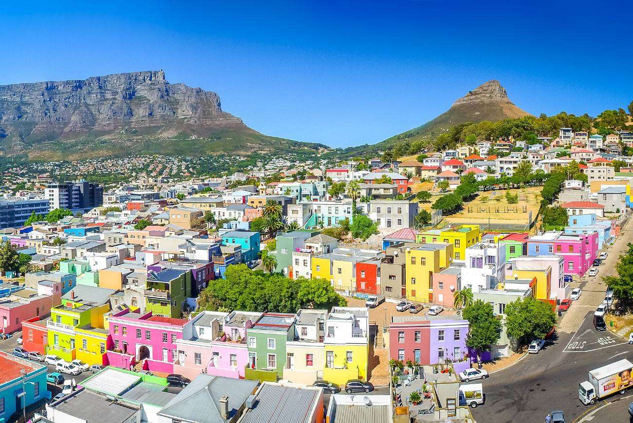 The painted houses of the Bo-Kaap climbing the slope of Signal Hill, with Table Mountain and Lion&rsquo;s Head behind