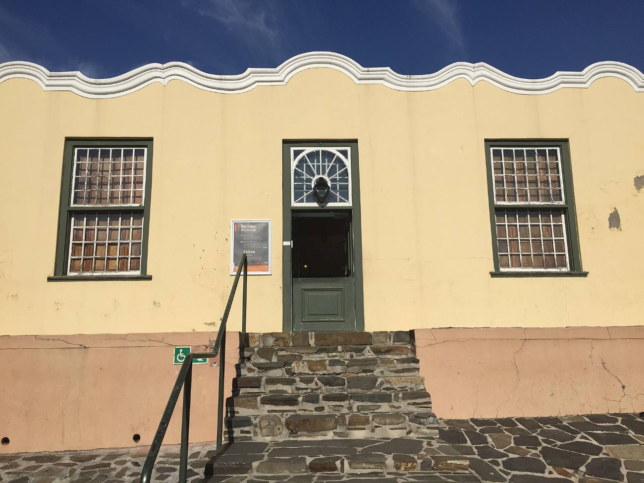 The pale yellow front of the Bo-Kaap Museum with its stoep and steps