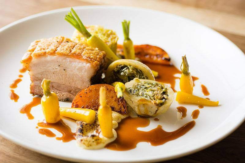 A beautifully plated dish of pork belly and vegetables