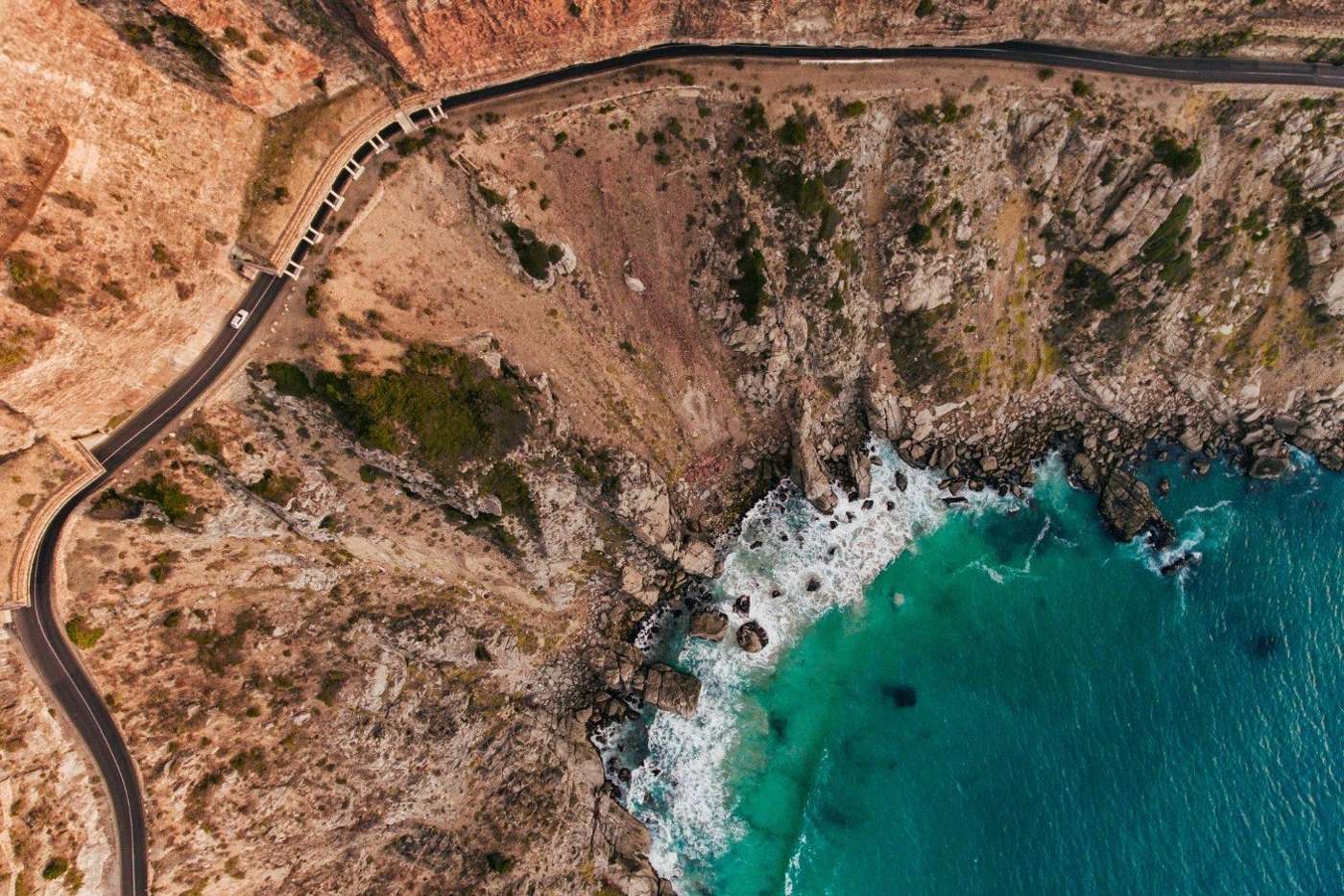 Chapman's Peak Drive from directly above, the road winding over the cliffs beside turquoise sea
