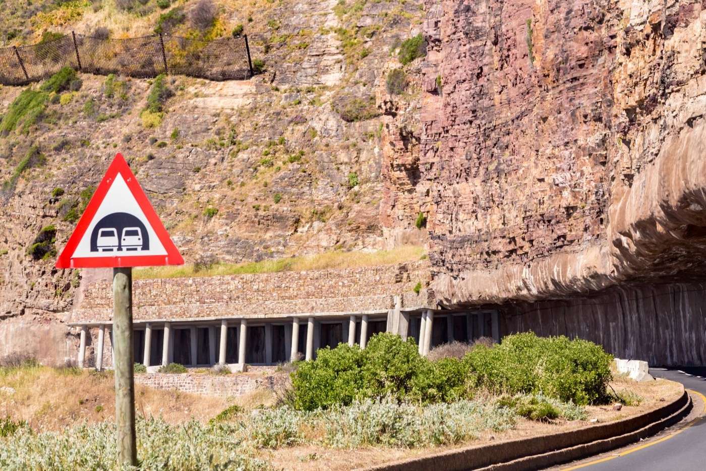 The half-tunnel carved into the cliff, with a road sign in front