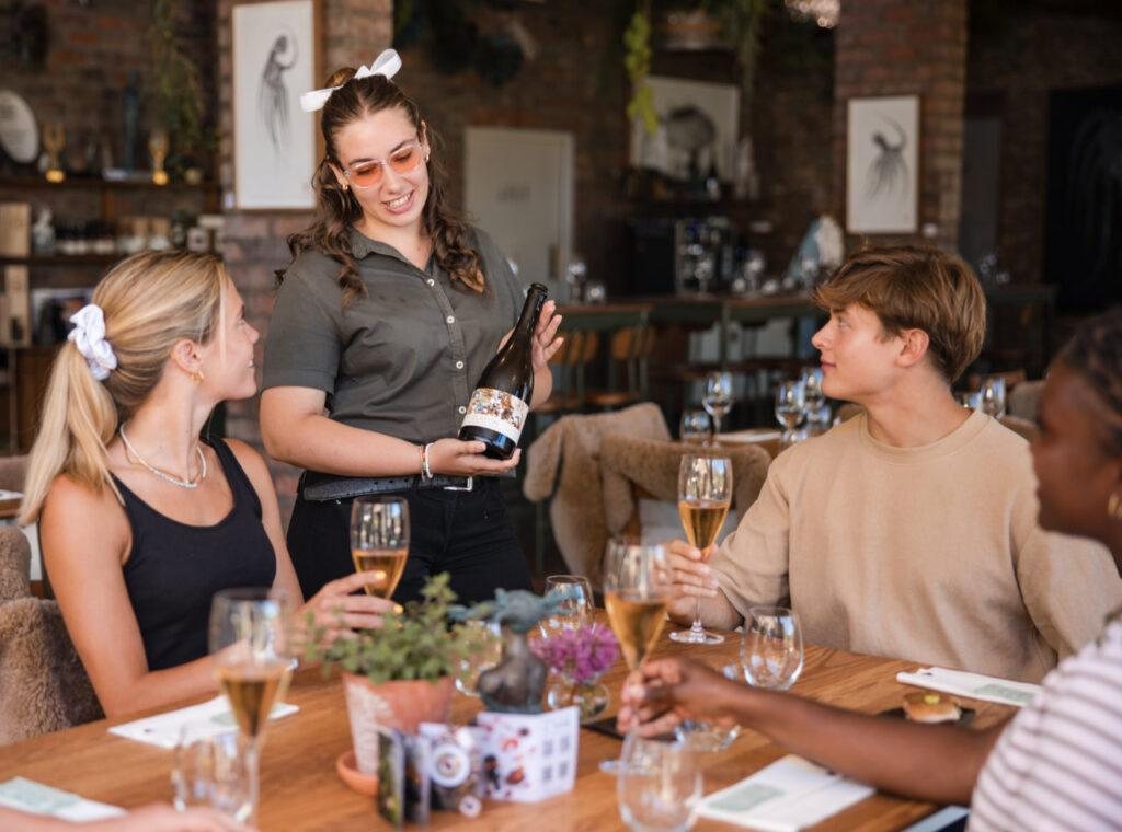 Guests at a table in the Creation tasting room, with a host pouring wine