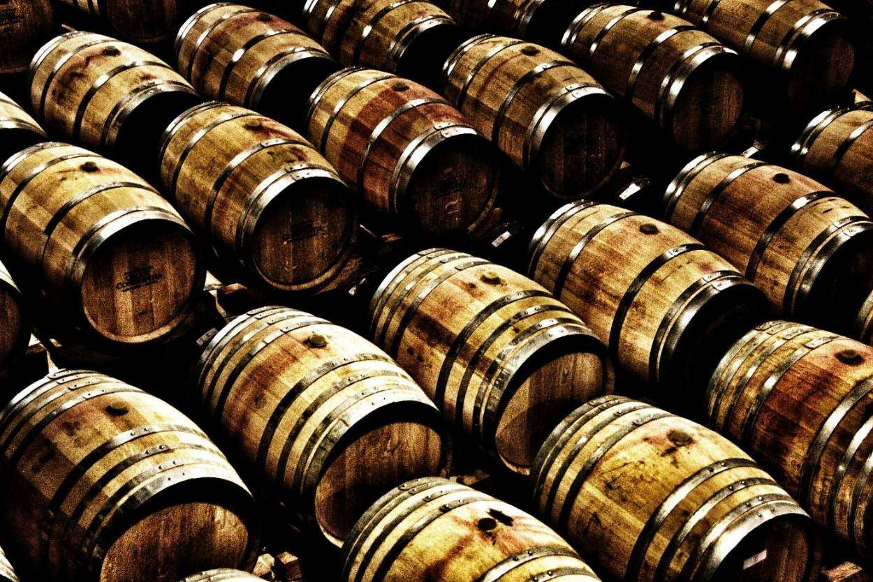 Rows of wooden wine barrels in a dim cellar