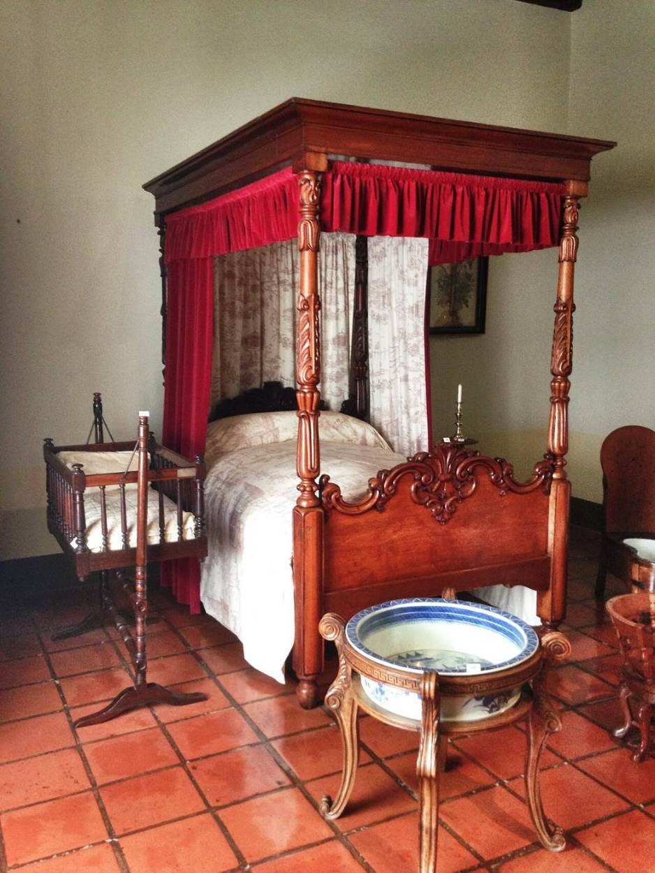 A bedroom with a four-poster bed and old furniture