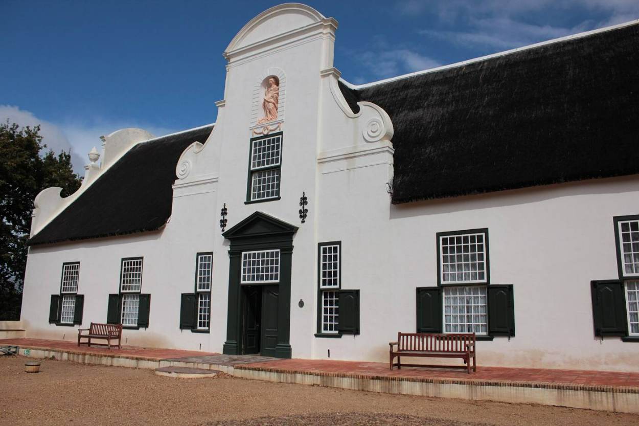 The white Cape Dutch manor house of Groot Constantia with its tall gable and thatched roof
