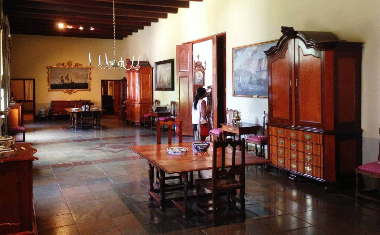 A furnished room in the manor with an old cabinet and dining table