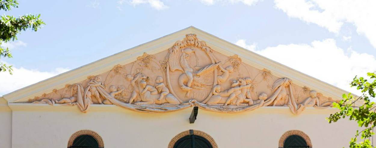 A detailed carved pediment on the gable of the Cloete Cellar