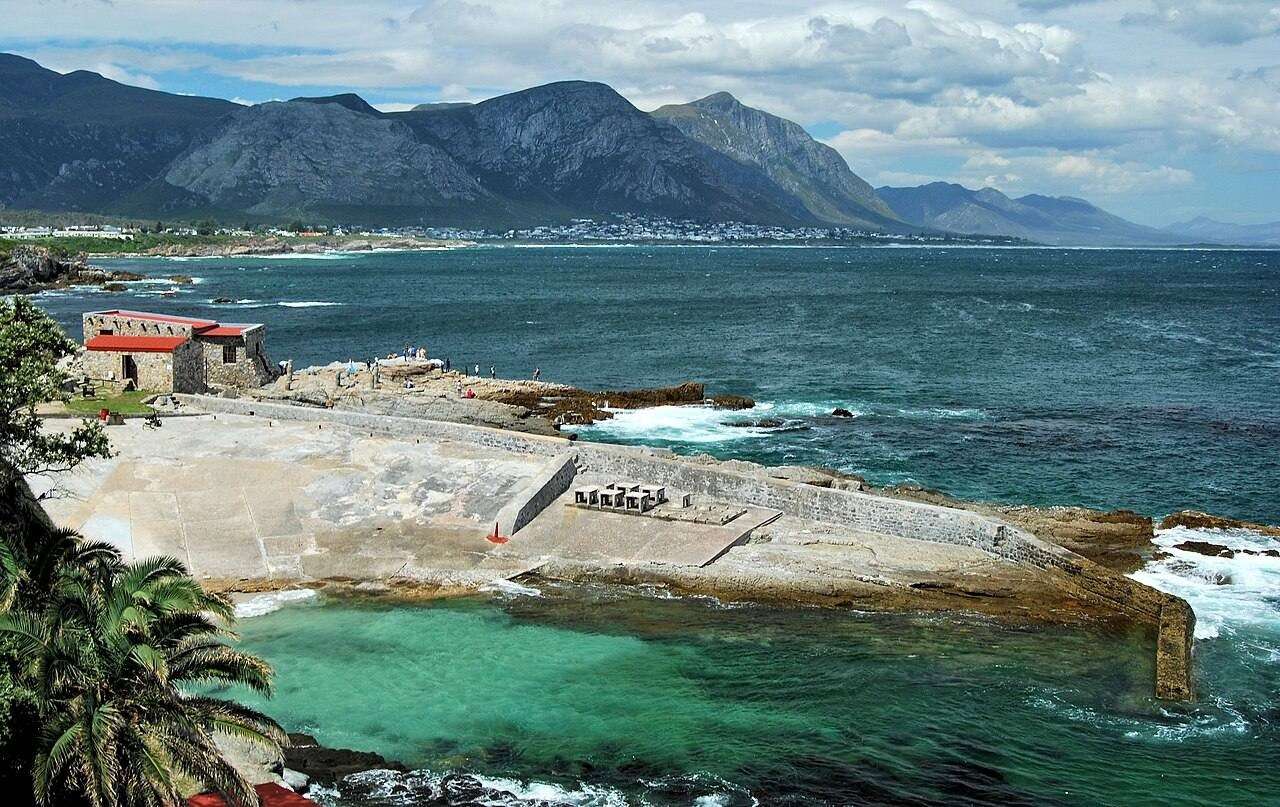 The stone Old Harbour of Hermanus with the mountains behind