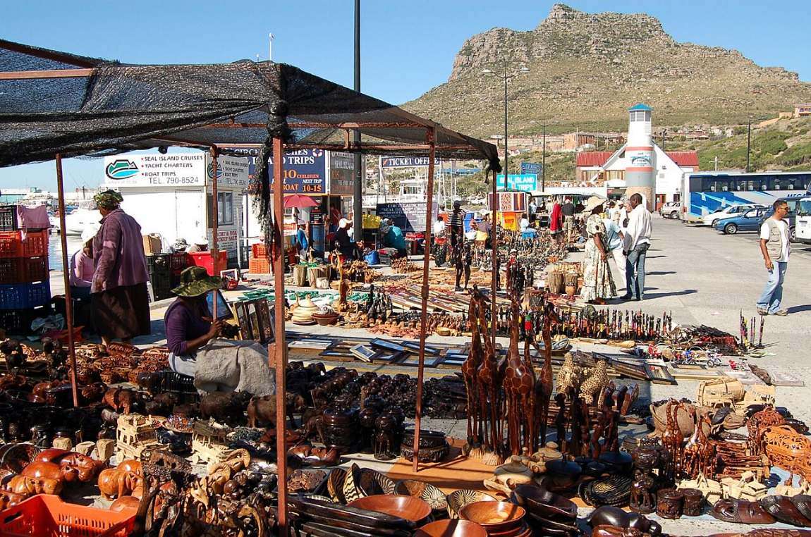 Stalls of carvings and crafts on the harbour front with the mountain behind