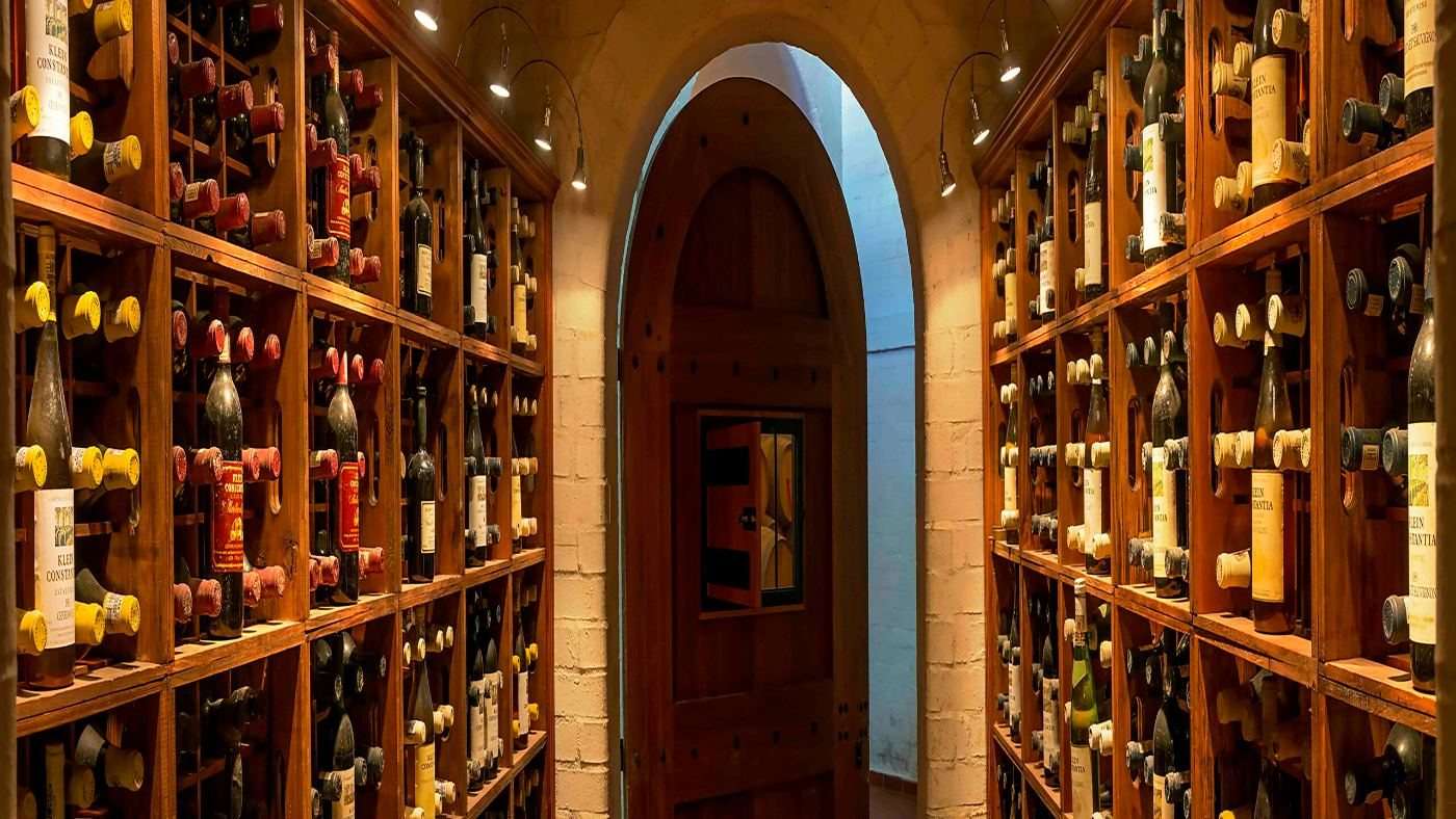 Walls of wine bottles in wooden racks around an arched doorway