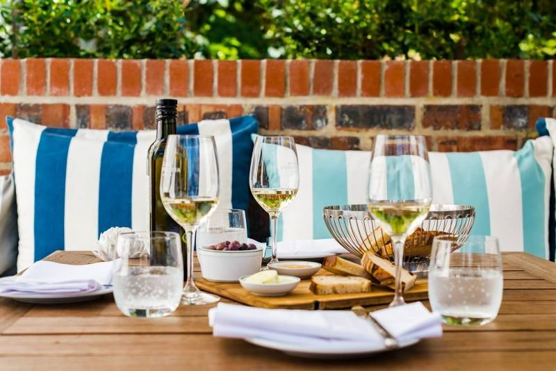 Glasses of white wine and a platter on a table with striped cushions