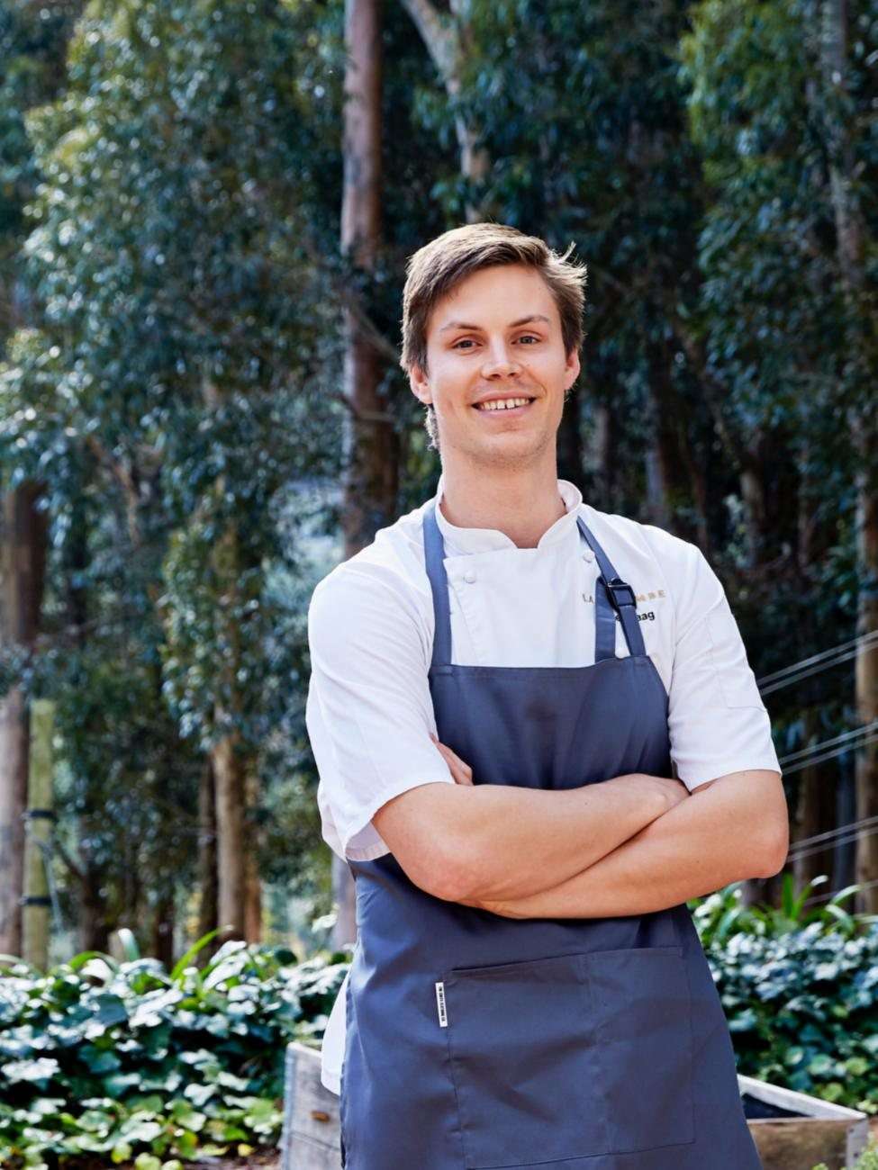 Chef James Gaag in an apron, standing among trees