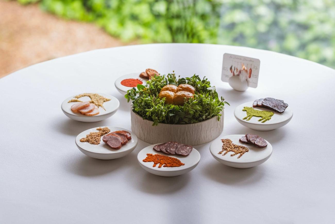Several small dishes around a central bowl of greens on a white table