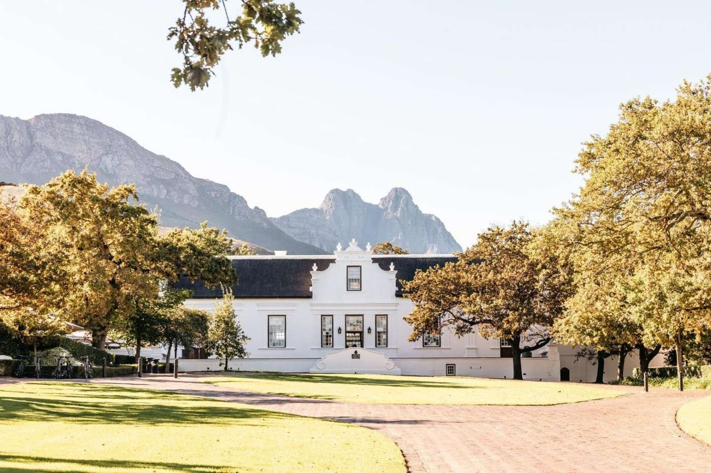 The white-gabled Manor House at Lanzerac among old oaks, with the Jonkershoek mountains behind