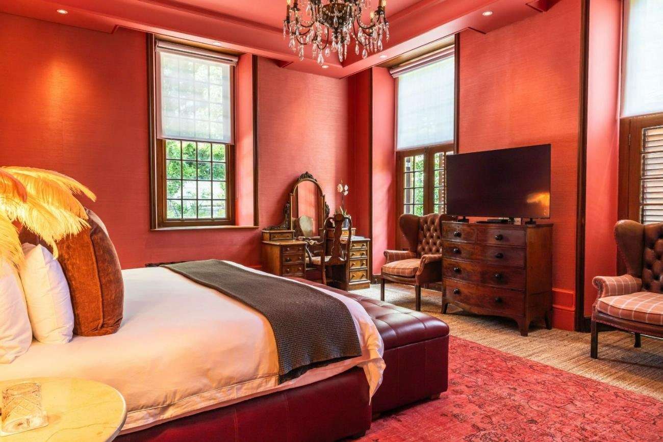 A suite with red walls, a large bed and antique furniture