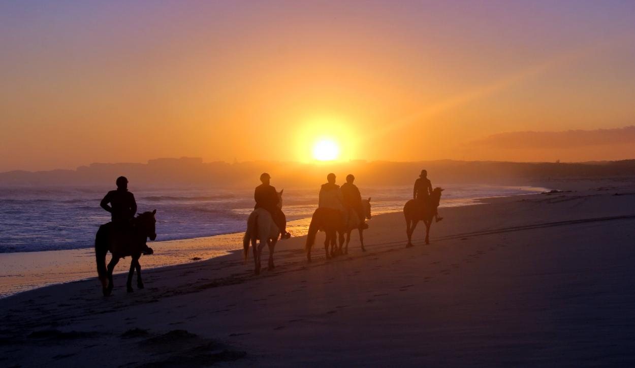 Riders heading home along the beach at sunset