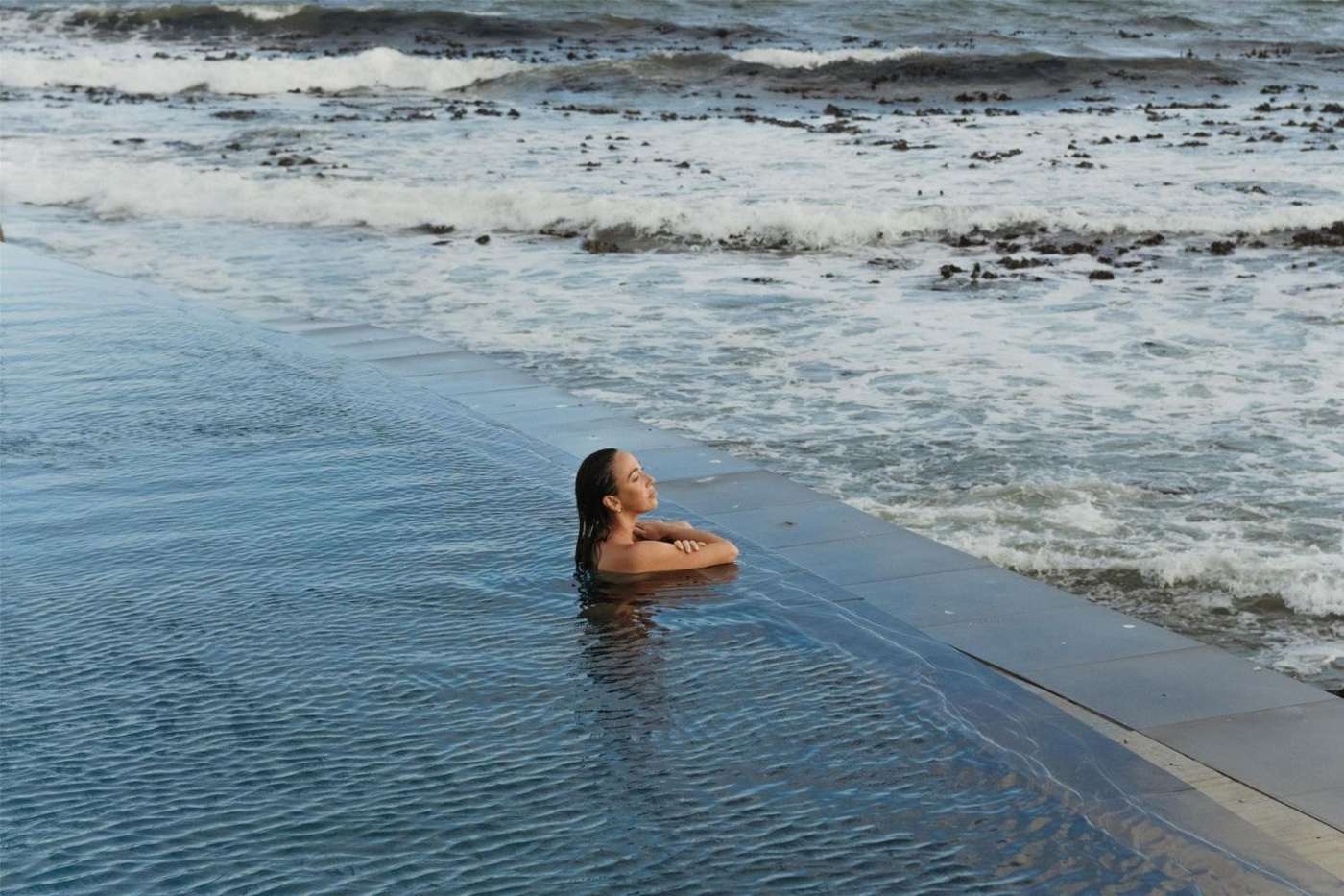 A swimmer in the infinity pool at the edge of the sea