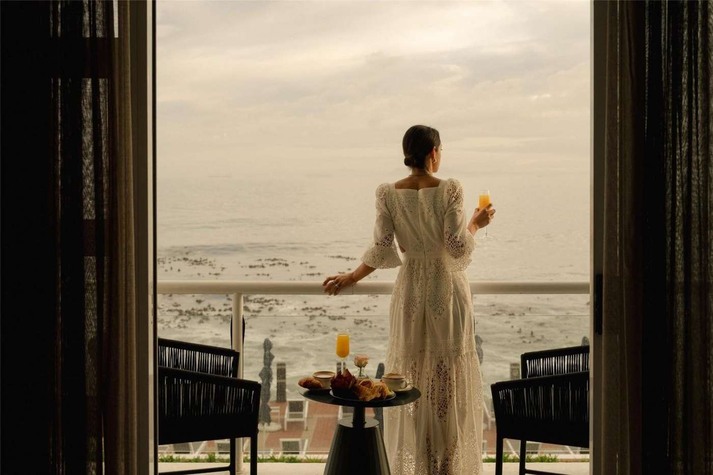A guest on a balcony looking out over the ocean at first light