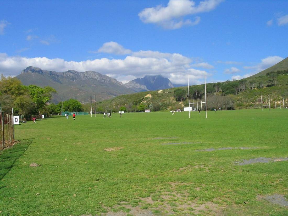 Green playing fields with mountains rising behind