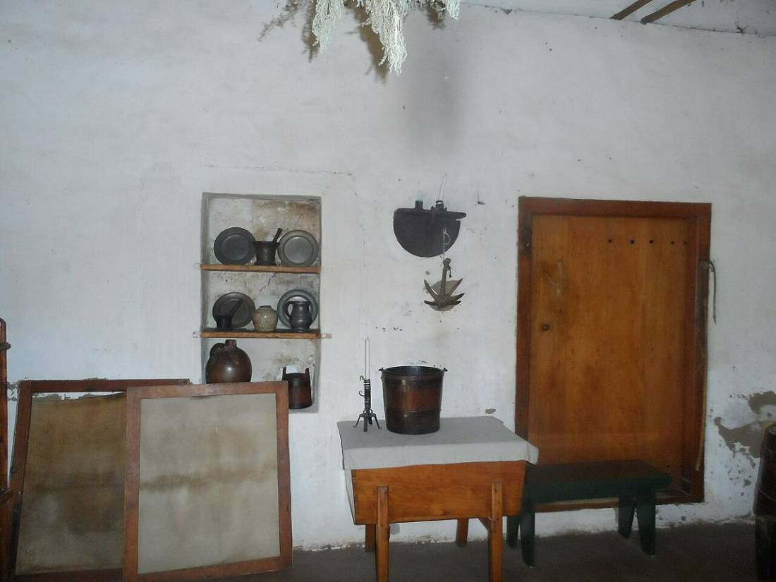 A simple old kitchen with copper pots, a wooden table and a door