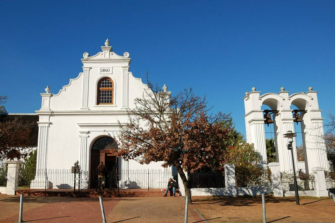 A white church with an ornate gable and a separate bell tower