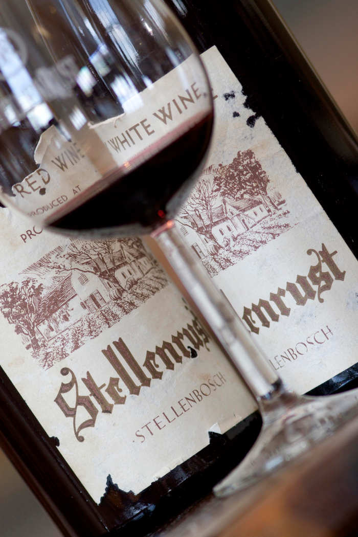 A glass of red wine resting on old Stellenrust wine labels